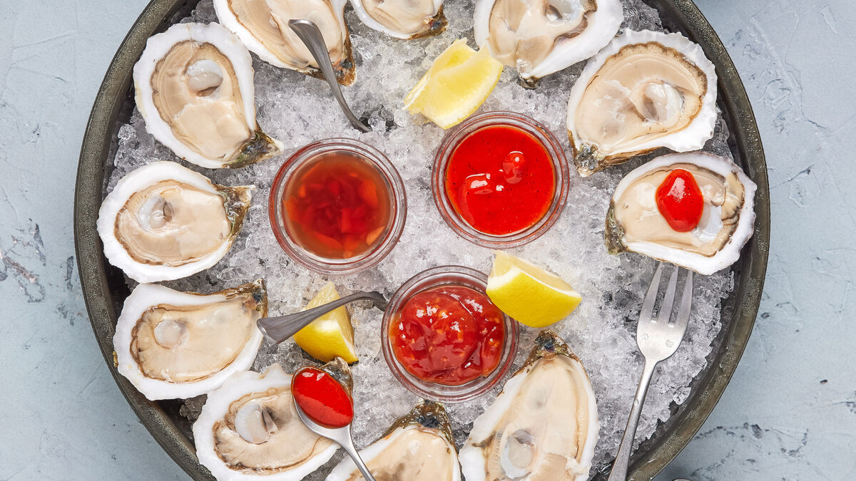 A tray of oysters with sauce in the middle