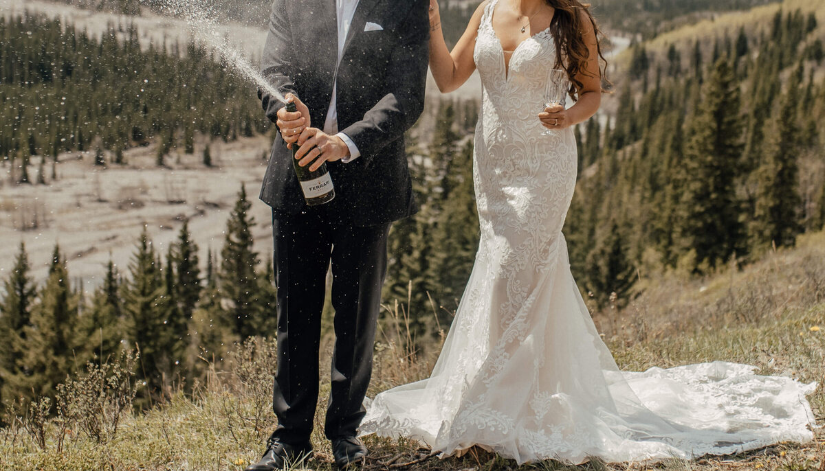 Bride and groom celebrate on mountain top with champagne