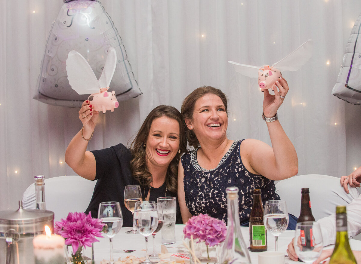 Gay brides posing with flying pigs at wedding reception
