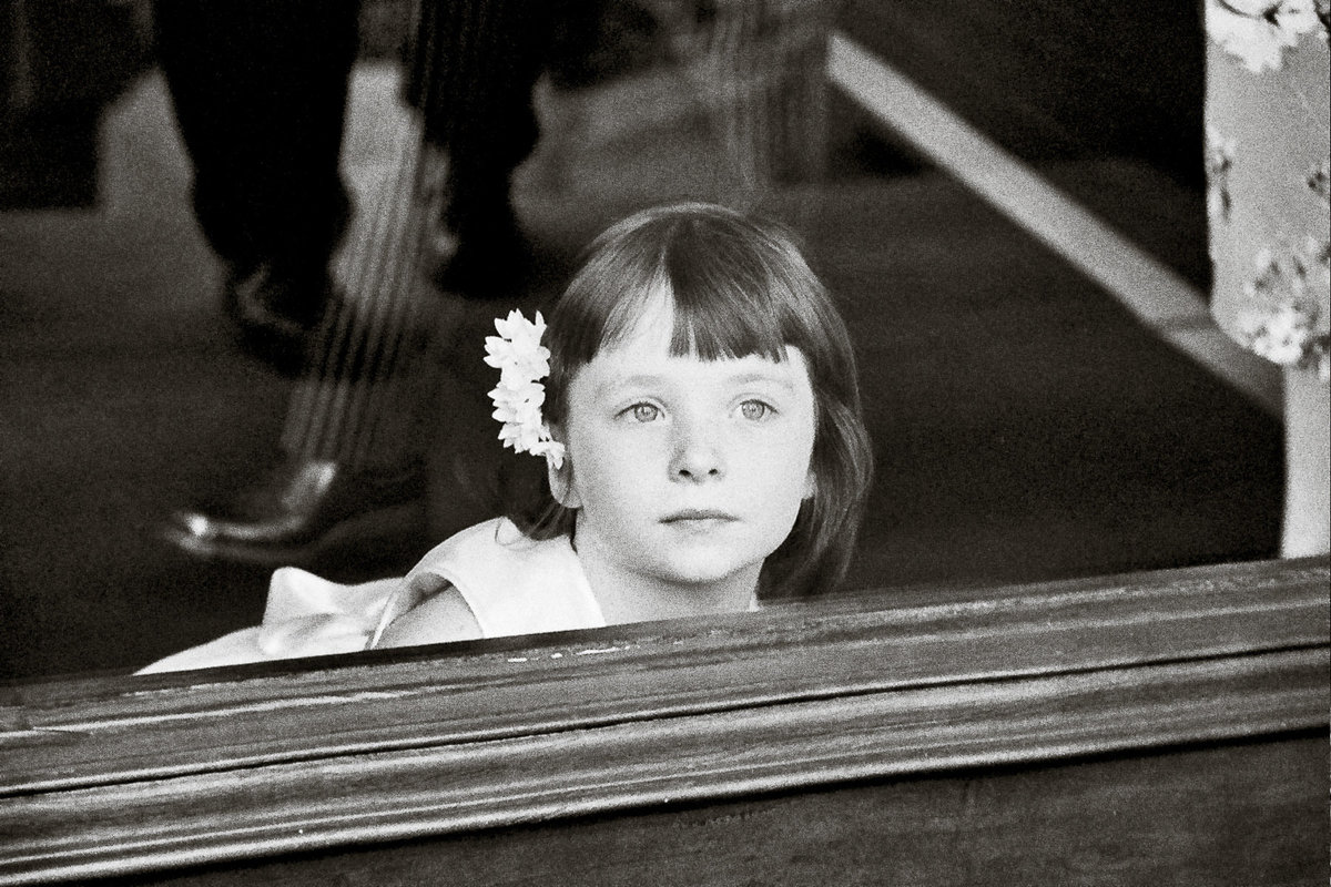 A flowergirl peering outside at a wedding in San Francisco.
