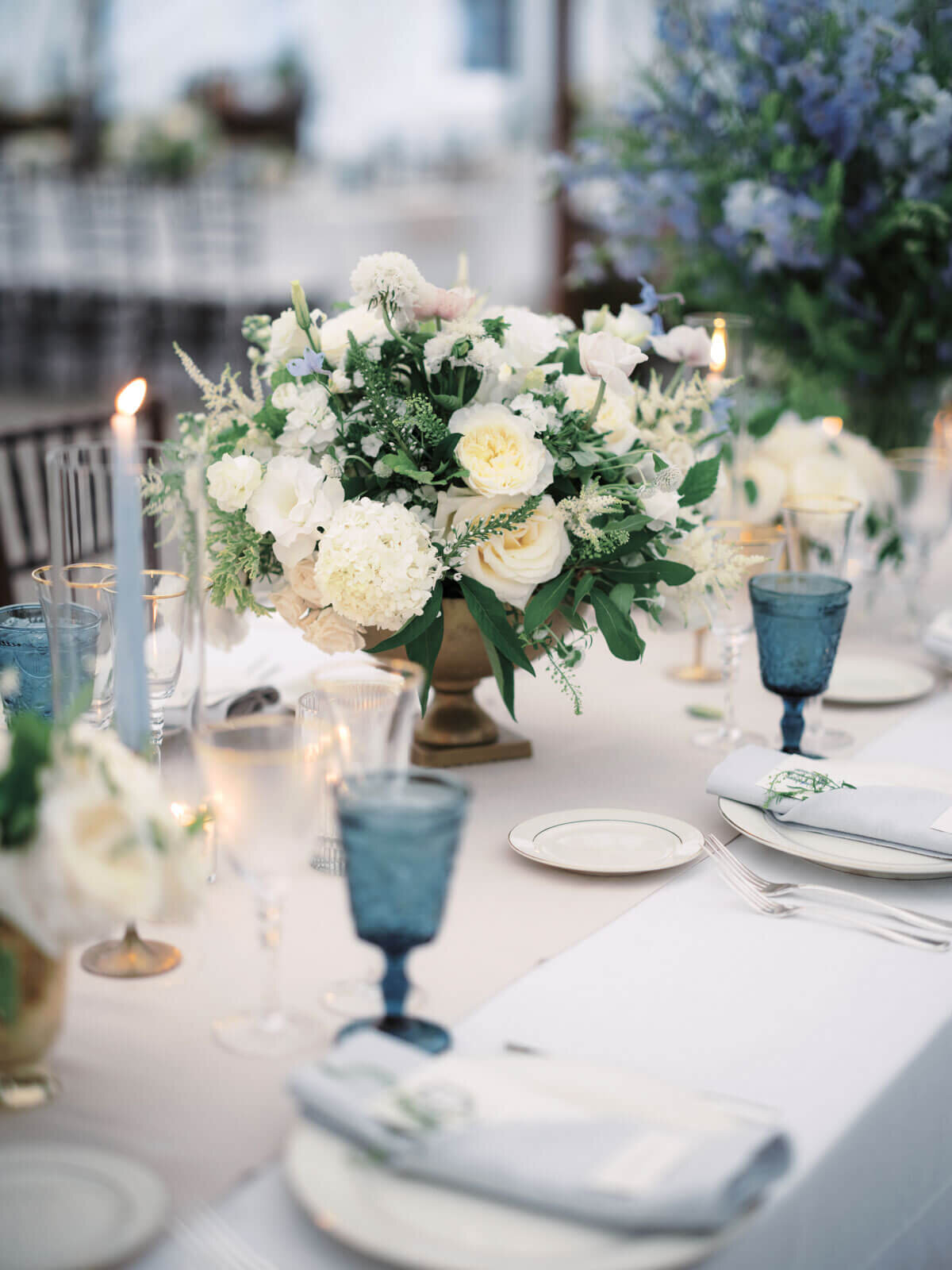 An elegant dining table with a white flower centerpiece, cutleries, and wine glasses at The Lion Rock Farm, CT. Image by Jenny Fu Studio