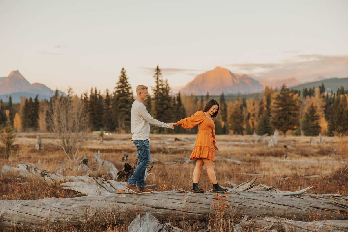 couple holding hands on log
