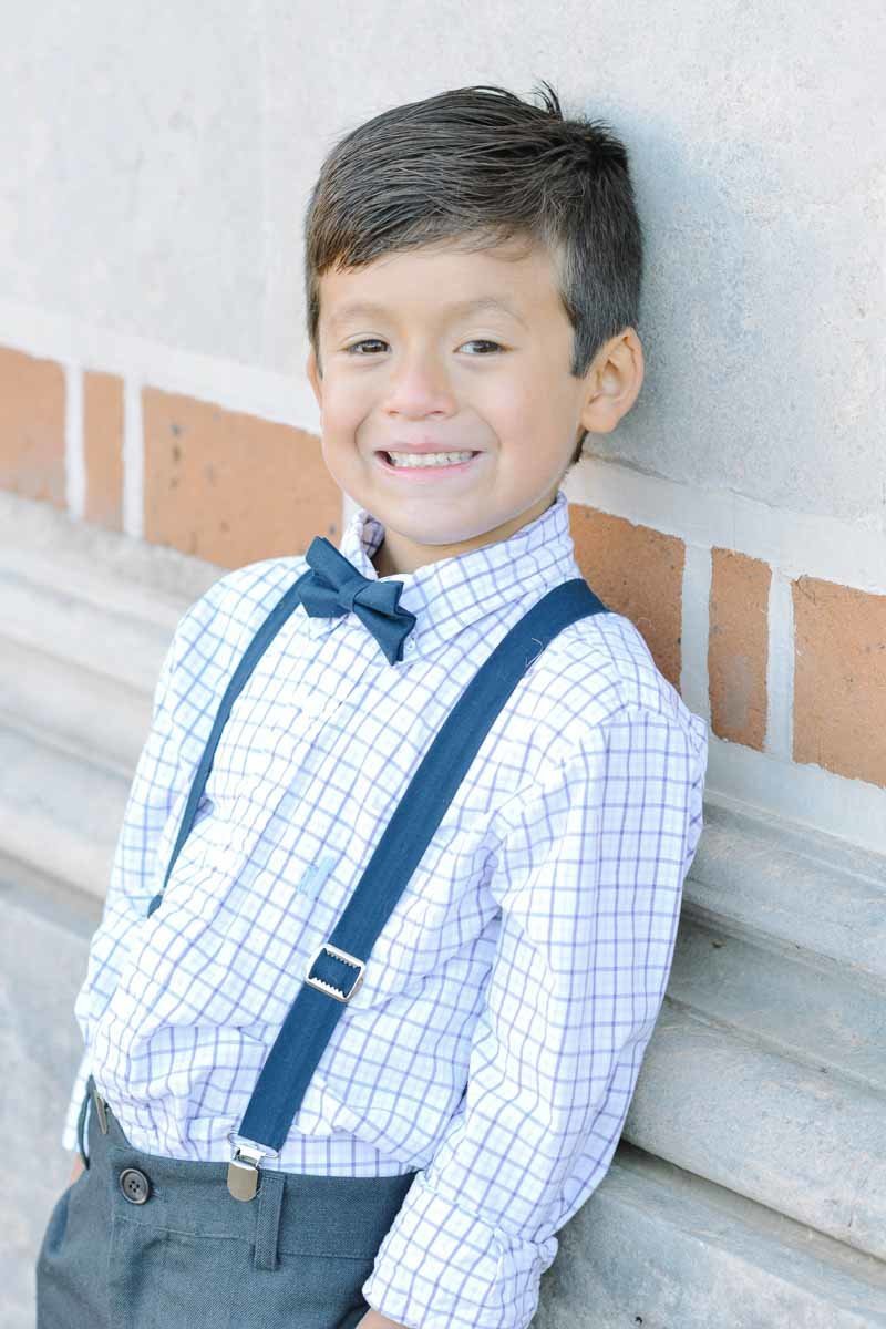 portrait of young boy in navy bowtie and suspenders
