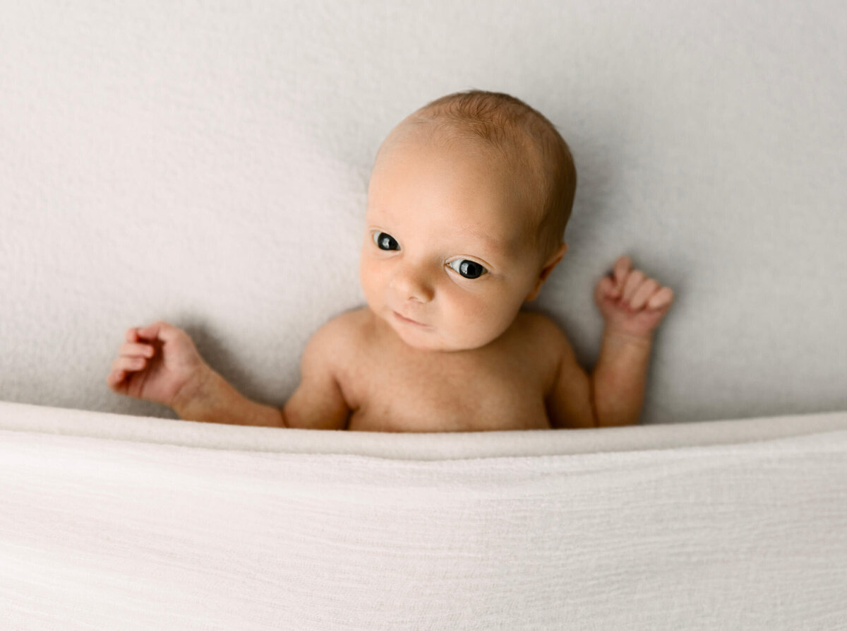 Newborn photo of a baby boy looking directly at the camera