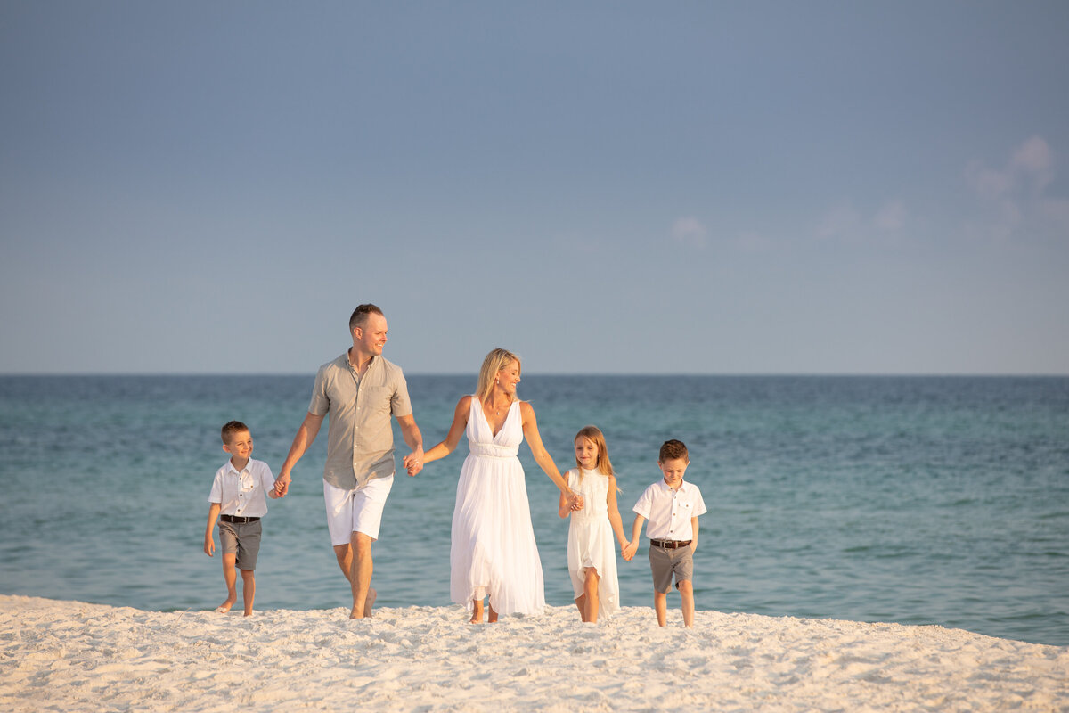 A family holding hands and walking along the sand at a beach