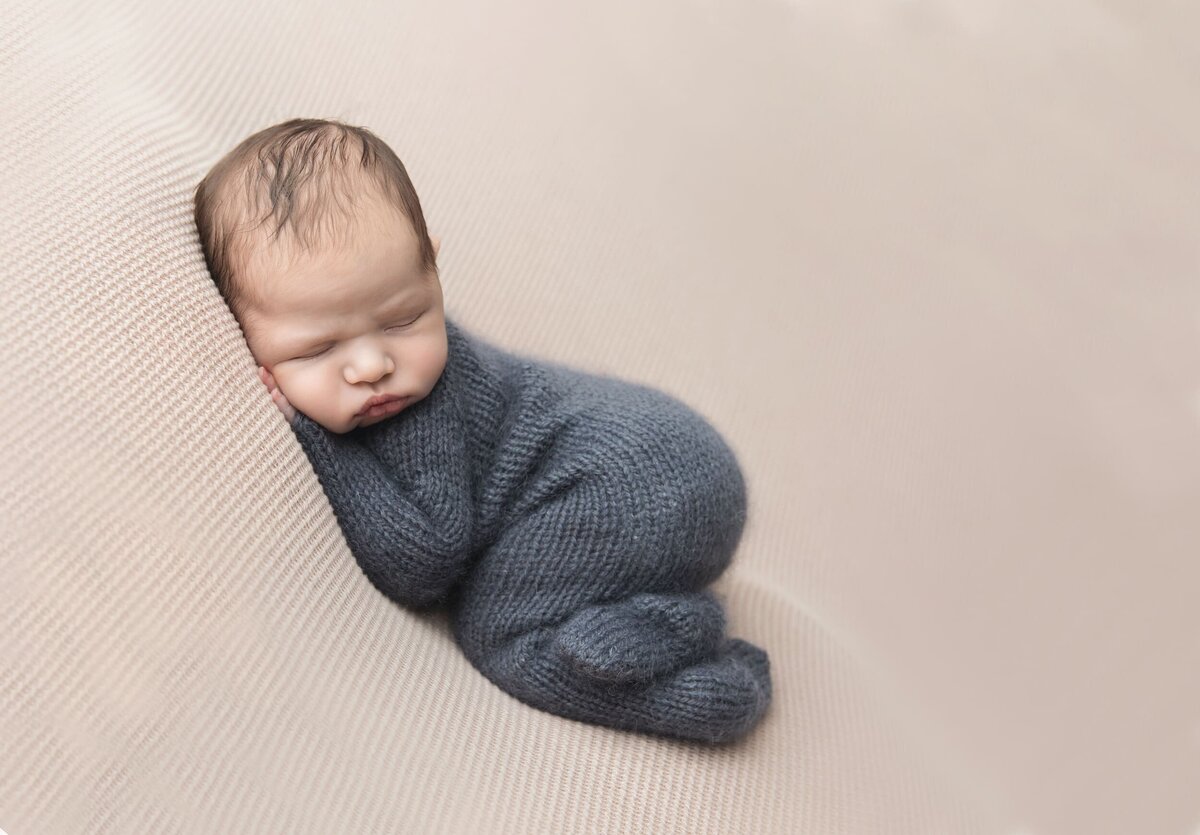 sleeping newborn in blue knit swaddle