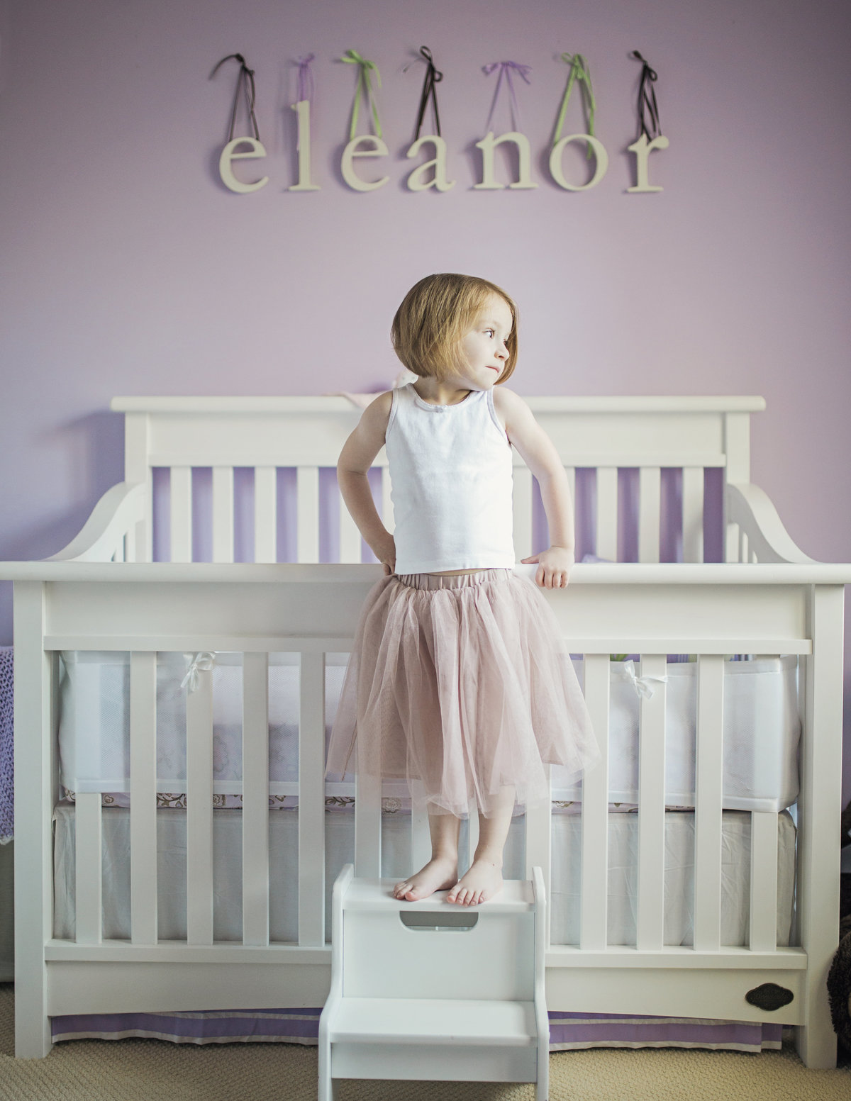 charlotte family photographer creates a beautiful lifestyle portrait of big sister standing by the new baby's crib