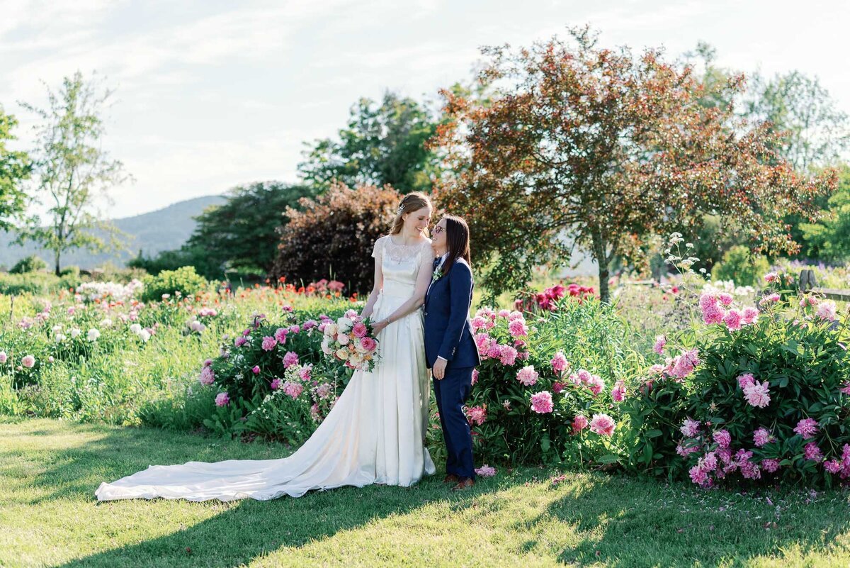 bride and bride embrace surrounded by pink peonies at trapp family lodge vt