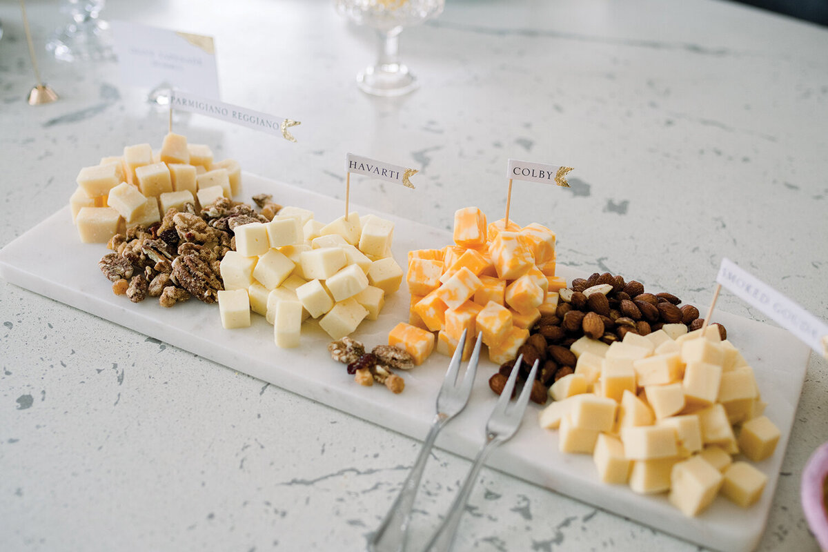 Cheese cubes arranged on a stylish marble platter at a pink and yellow girl baby shower.