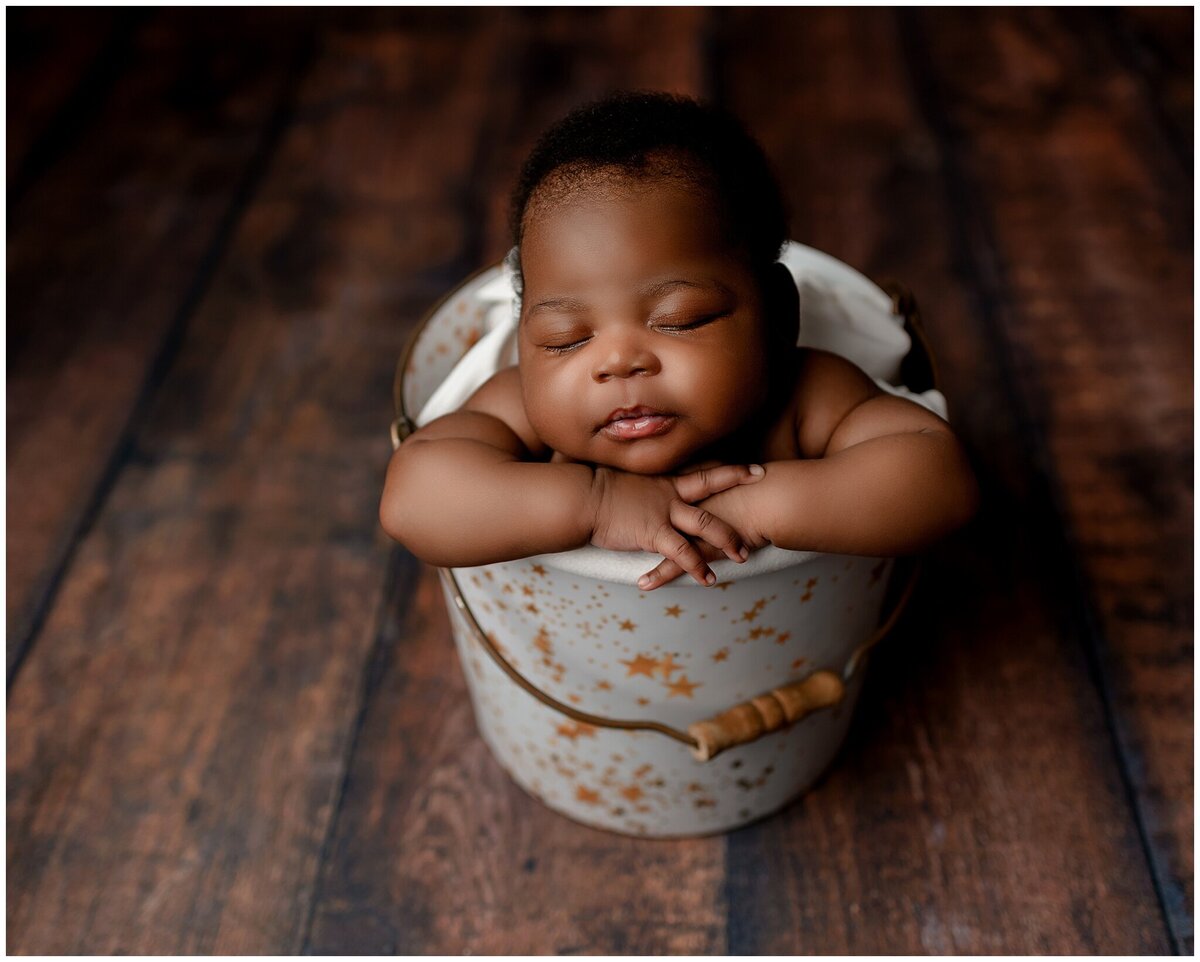 Newborn photography session with a baby in a bucket .