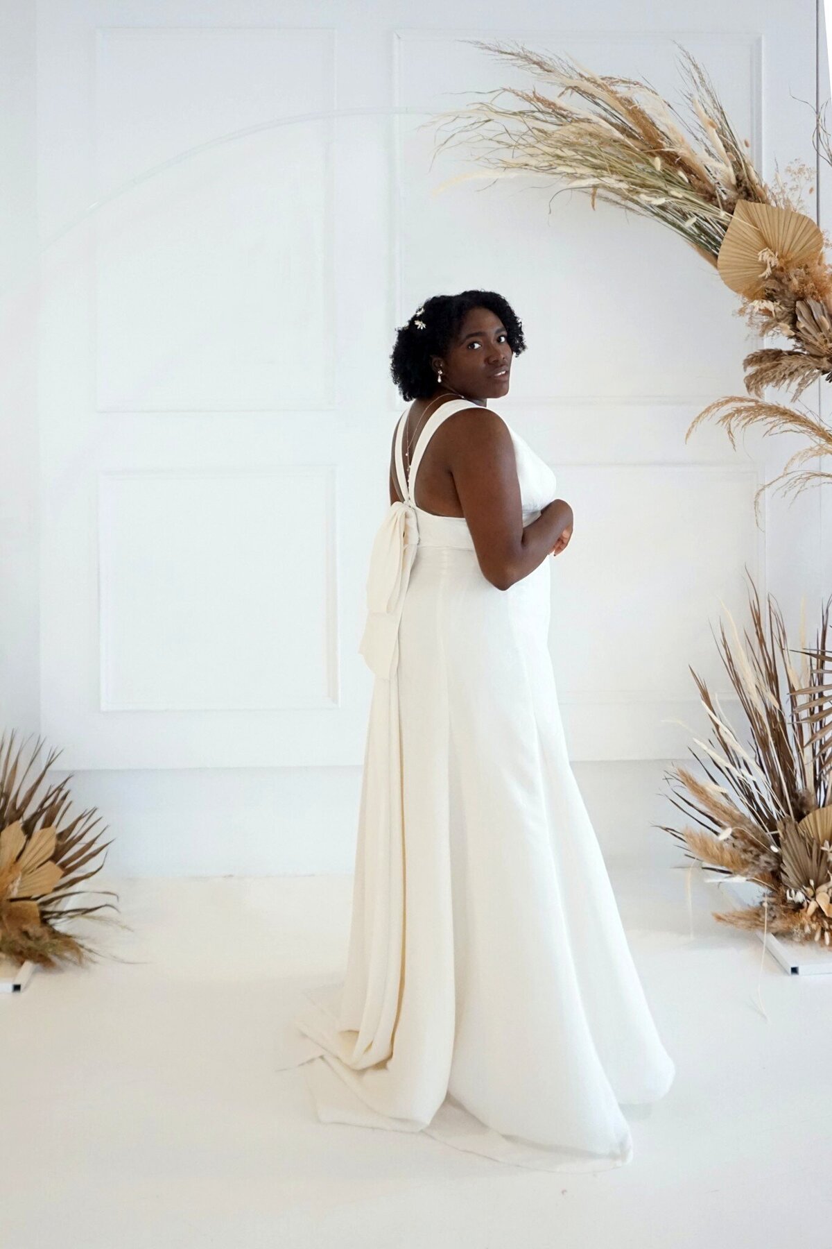 Side view of the Sol wedding dress style shows the detachable oversized bow train and a little peak of the v-back.