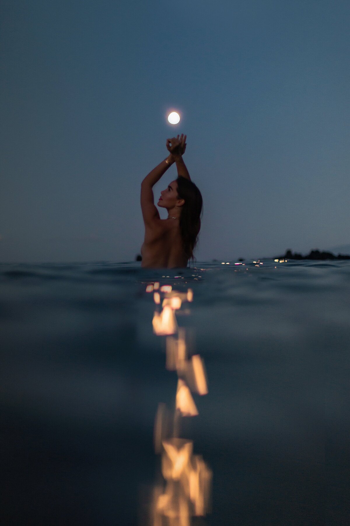 Stunning dark portrait of a woman posing in the water under the moon in Maui