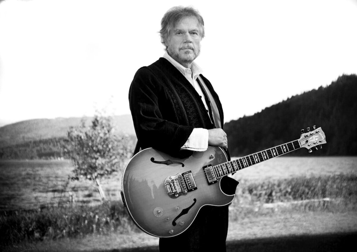 Randy Bachman branding musician portrait black and white standing with his guitar across his body in front of lake