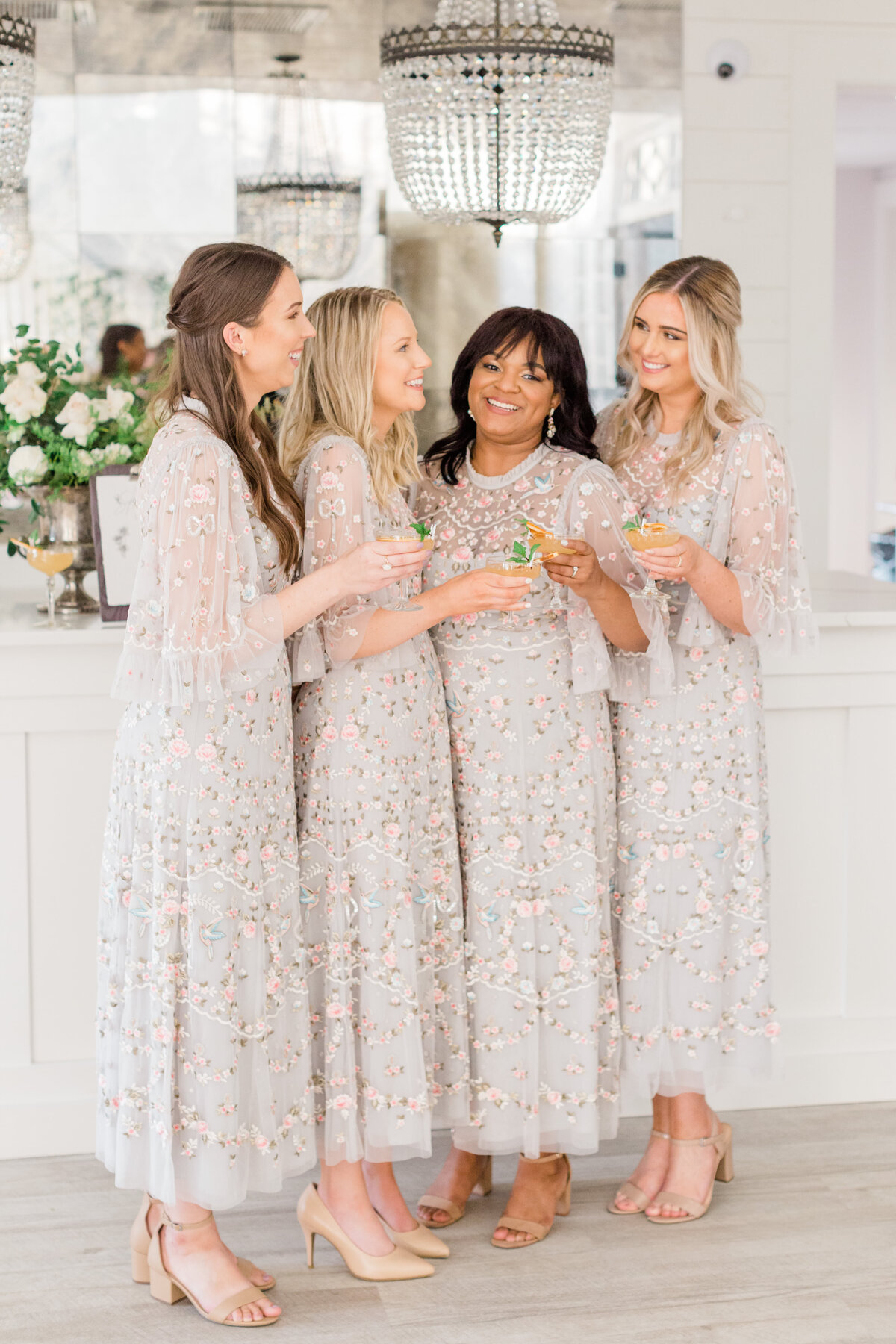 Bridesmaids clink their cocktail glasses at a wedding