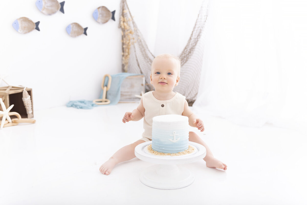A nautical themed toddler smashes a cake in a studio