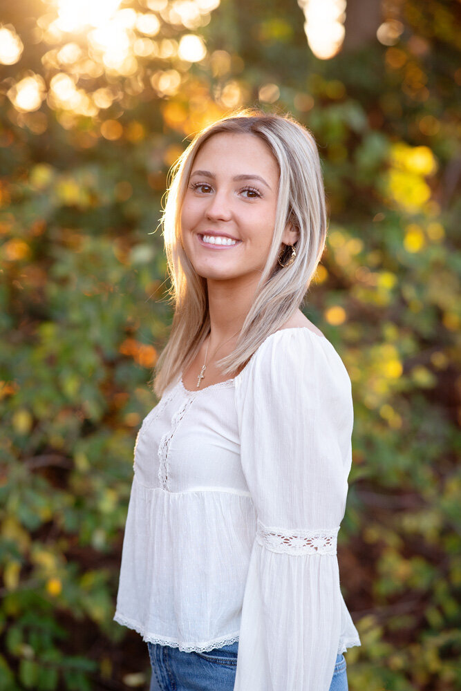 Senior session of young woman wearing a white top standing outside