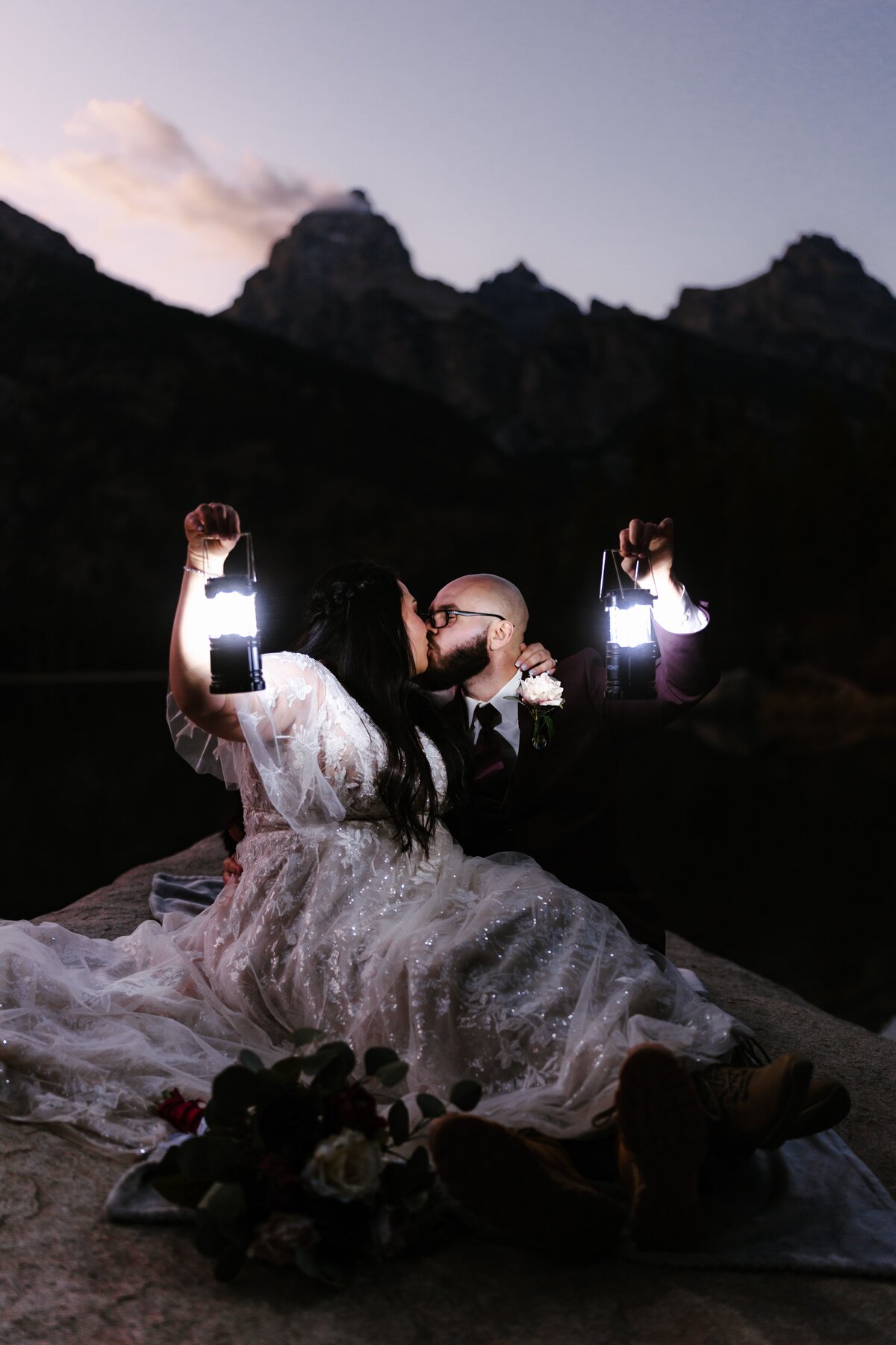 A couple kissing and holding lanterns on the shore of Taggart Lake in Grand Teton National Park