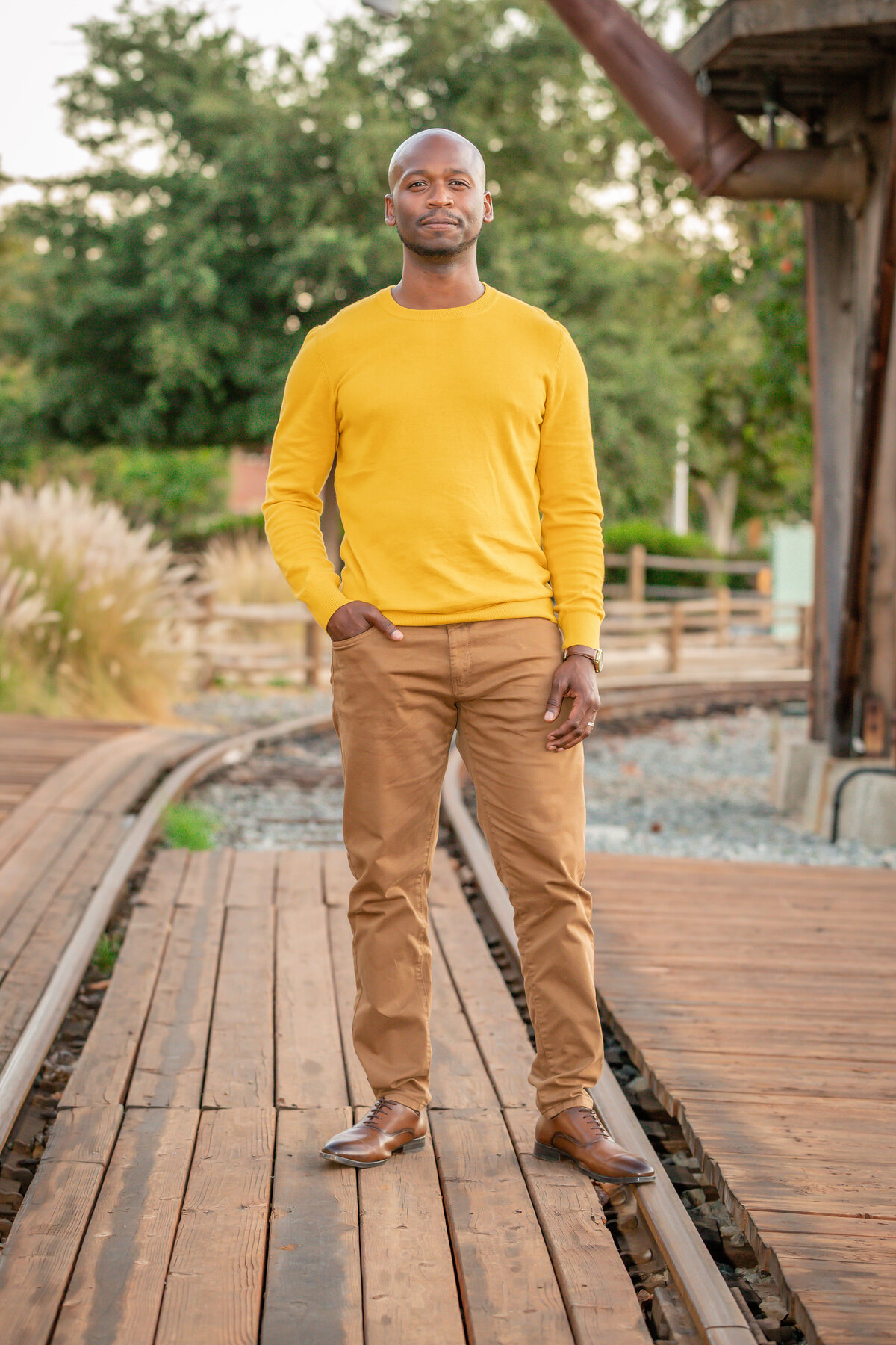 Black man in yellow standing in front of water tower