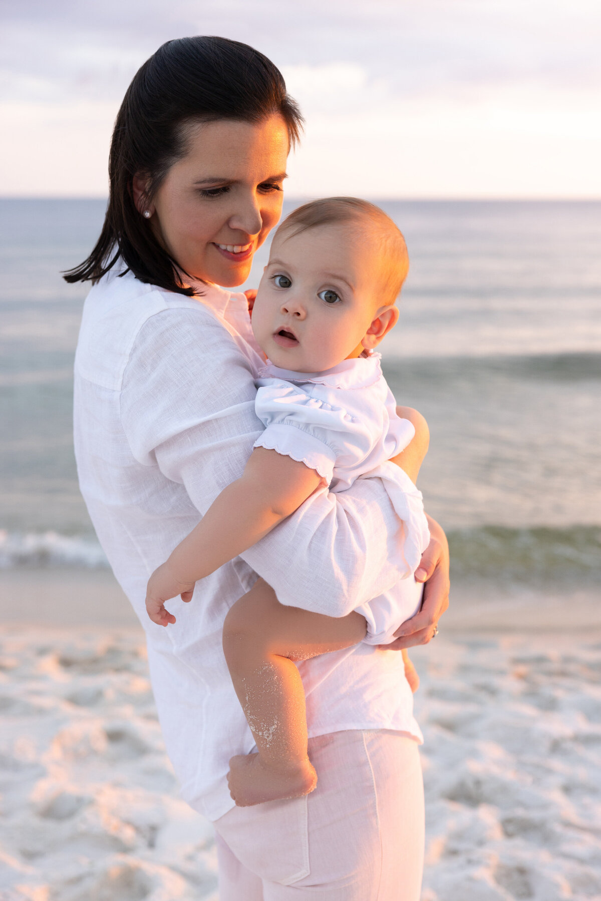 A mother holding a small baby at the beach