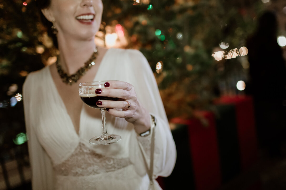 A bride holding an espresso martini cocktail at a speakeasy after party in Houston Texas. Captured by Fort Worth wedding photographer, Megan Christine Studio