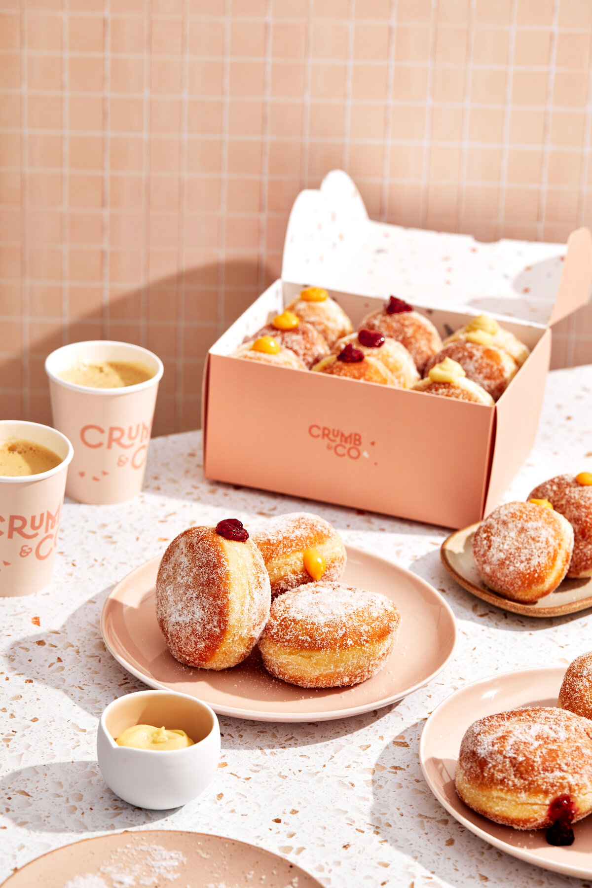 Cafe with a plate of donuts and jam donuts inside a takeaway box.