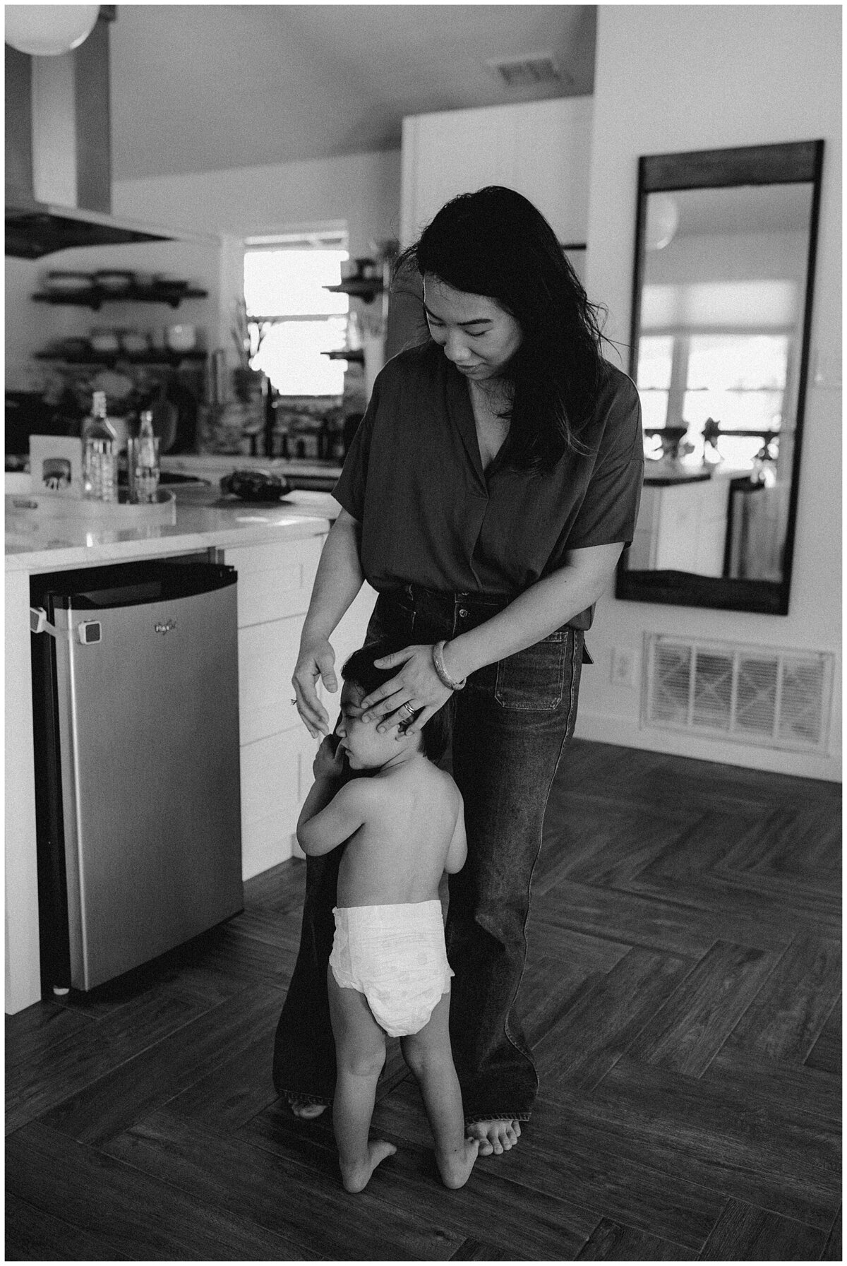 Mother with child in diaper in the kitchen at  family session at home in Austin Texas