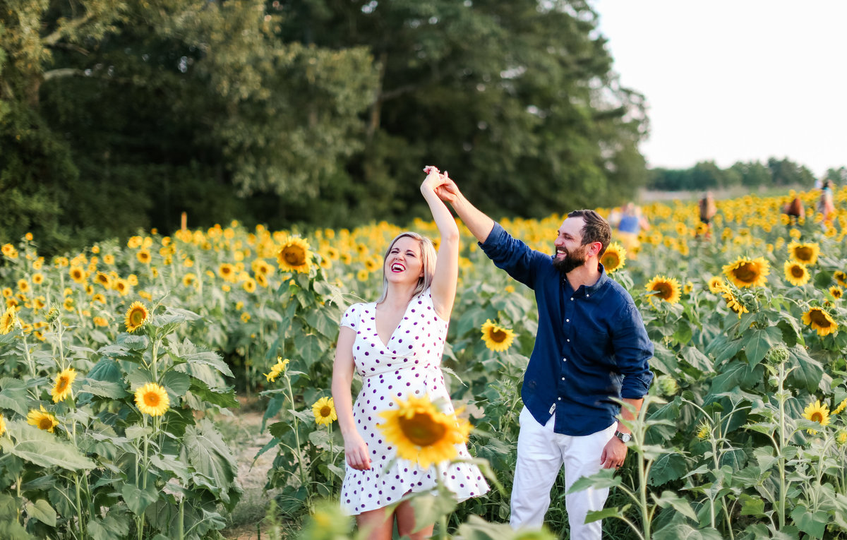 Engaged couple dances in sunflower field