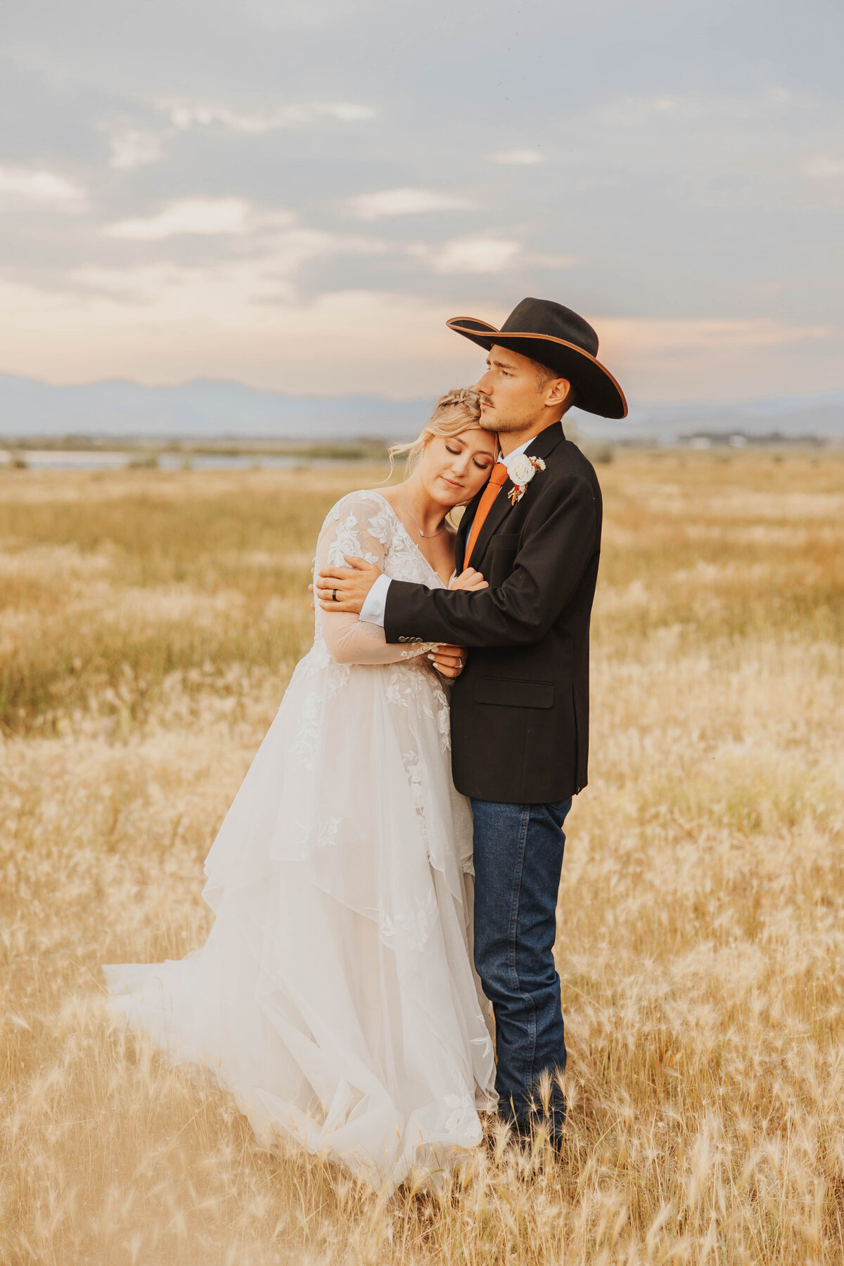 bride and groom embracing in field