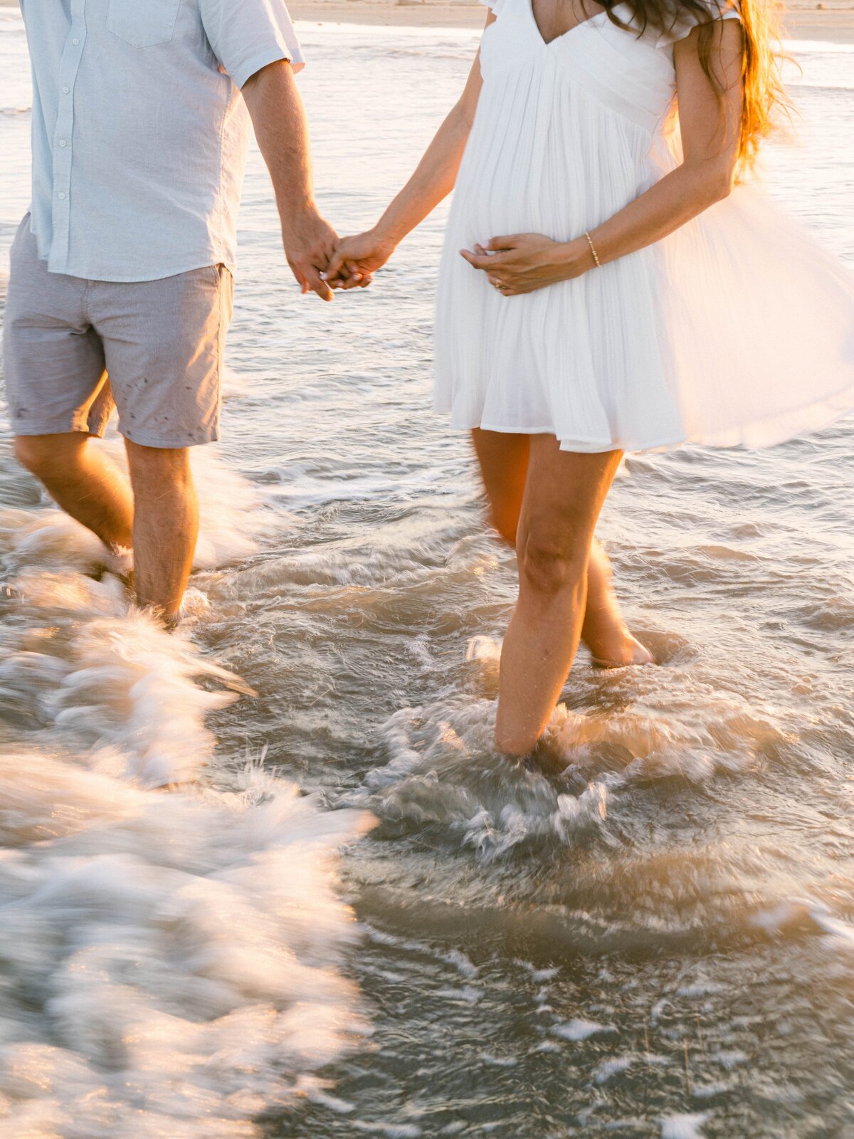Couple holding hands wading in the ocean