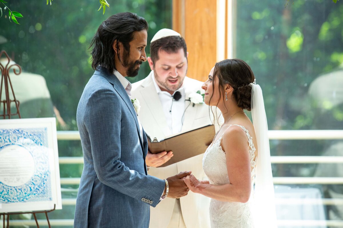 A bride and groom exchange vows in front of an officiant at a sunlit indoor wedding ceremony coordinated by a top Iowa wedding planner.