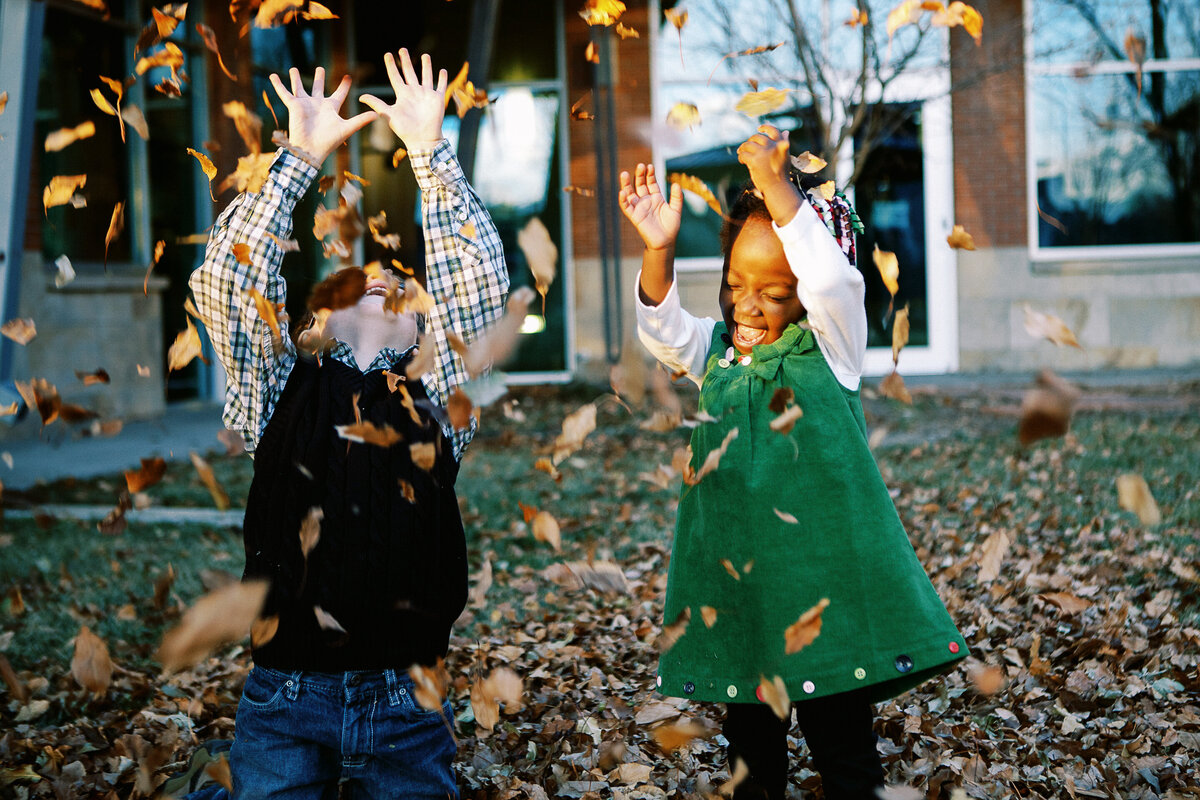 lifestyle photos of longmont brother and sister featuring leaf throwing