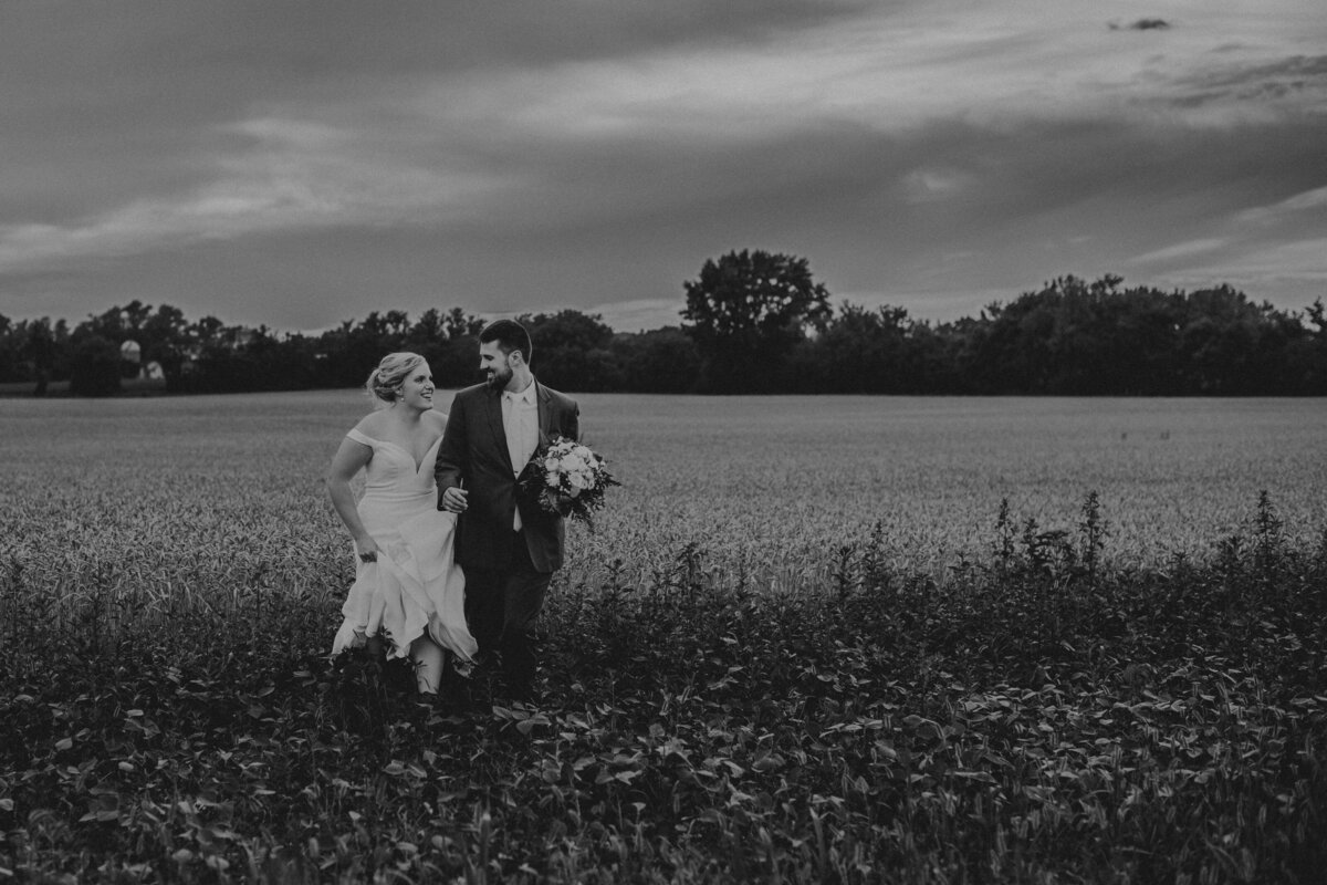 Bride and groom running and smiling at each other in a field