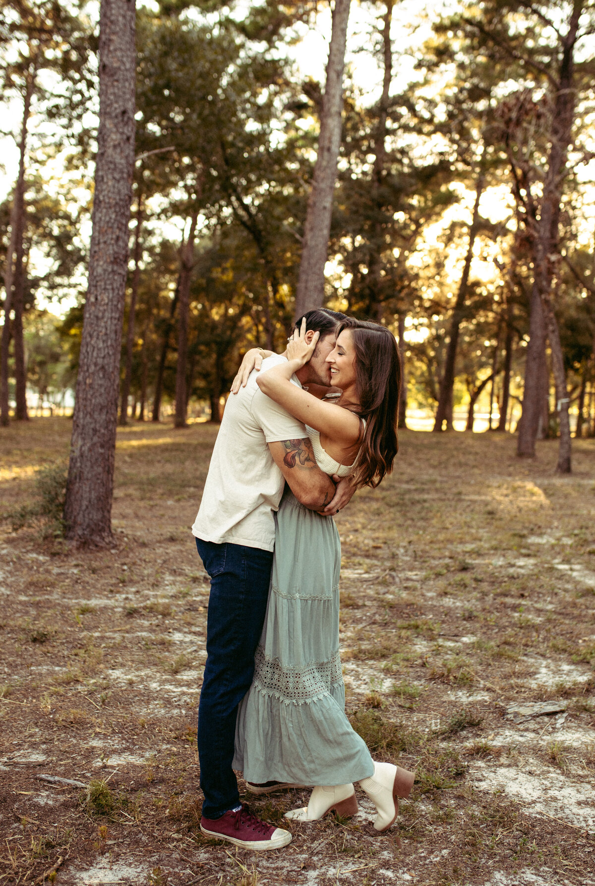 married couple embrace and dance at sunset under trees