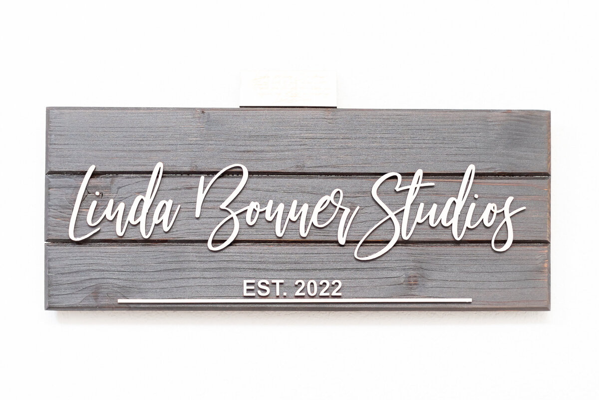 Wooden business sign with white letters during branding session in McKinney Texas captured by Allison Amores Photography