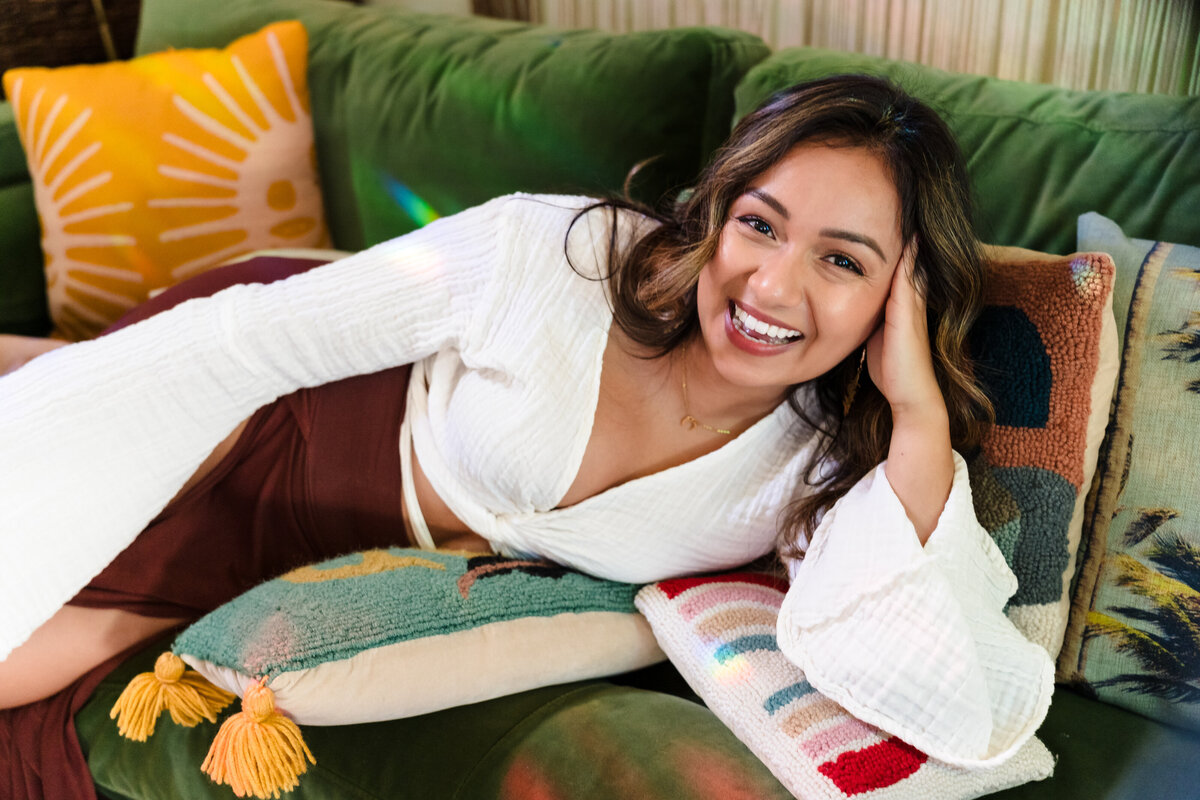 brand photo of a life Coach laying in a green sofa, hands in her head and smiles to the camera.