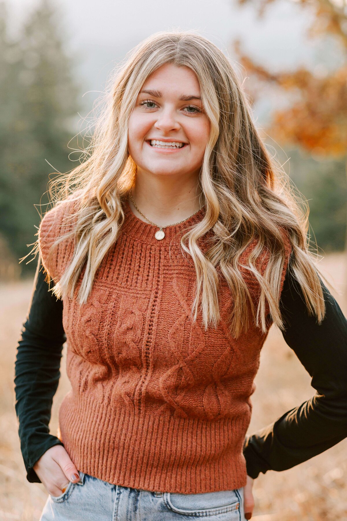 A teenage girl in a brown sweater with her hand on her hip smiles Fitton Green Corvallis OR Senior photography
