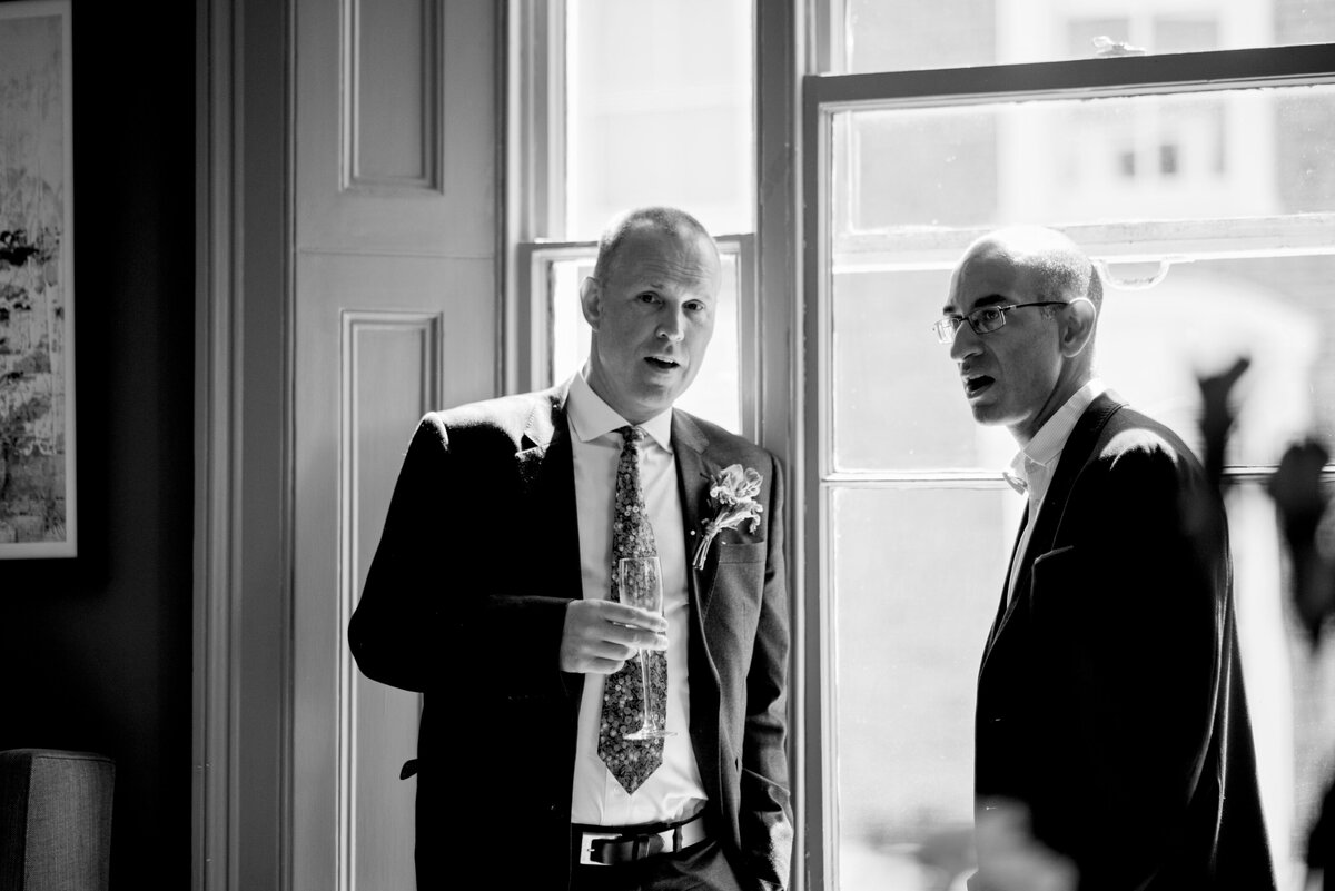 Black and white photography of a groom and one of his guests conversing taken by London Wedding Photographer Liberty Pearl