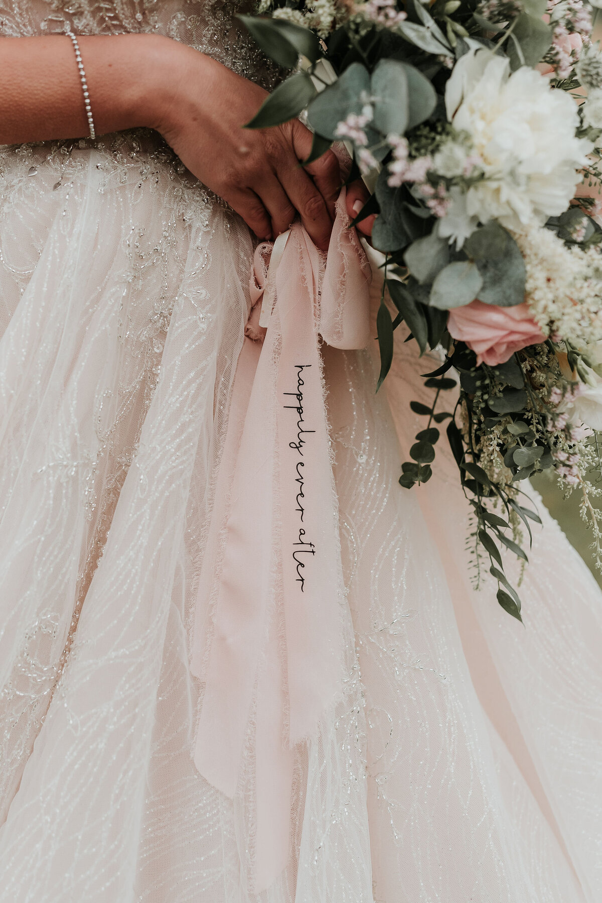 Blush pink ribbon on bridal bouquet with Happily Ever After writing at barn wedding at Odo's Barn, Ashford