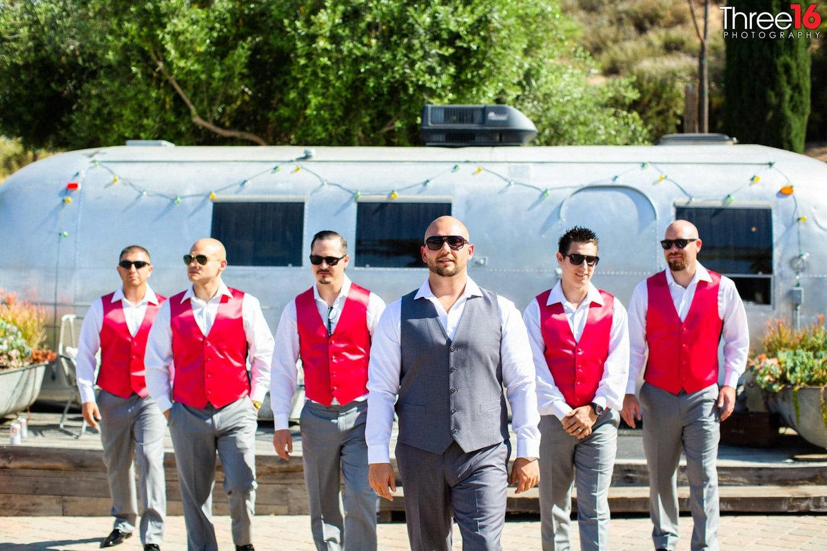 Groom and his Groomsmen walk towards the photographer wearing their wedding attire and sunglasses