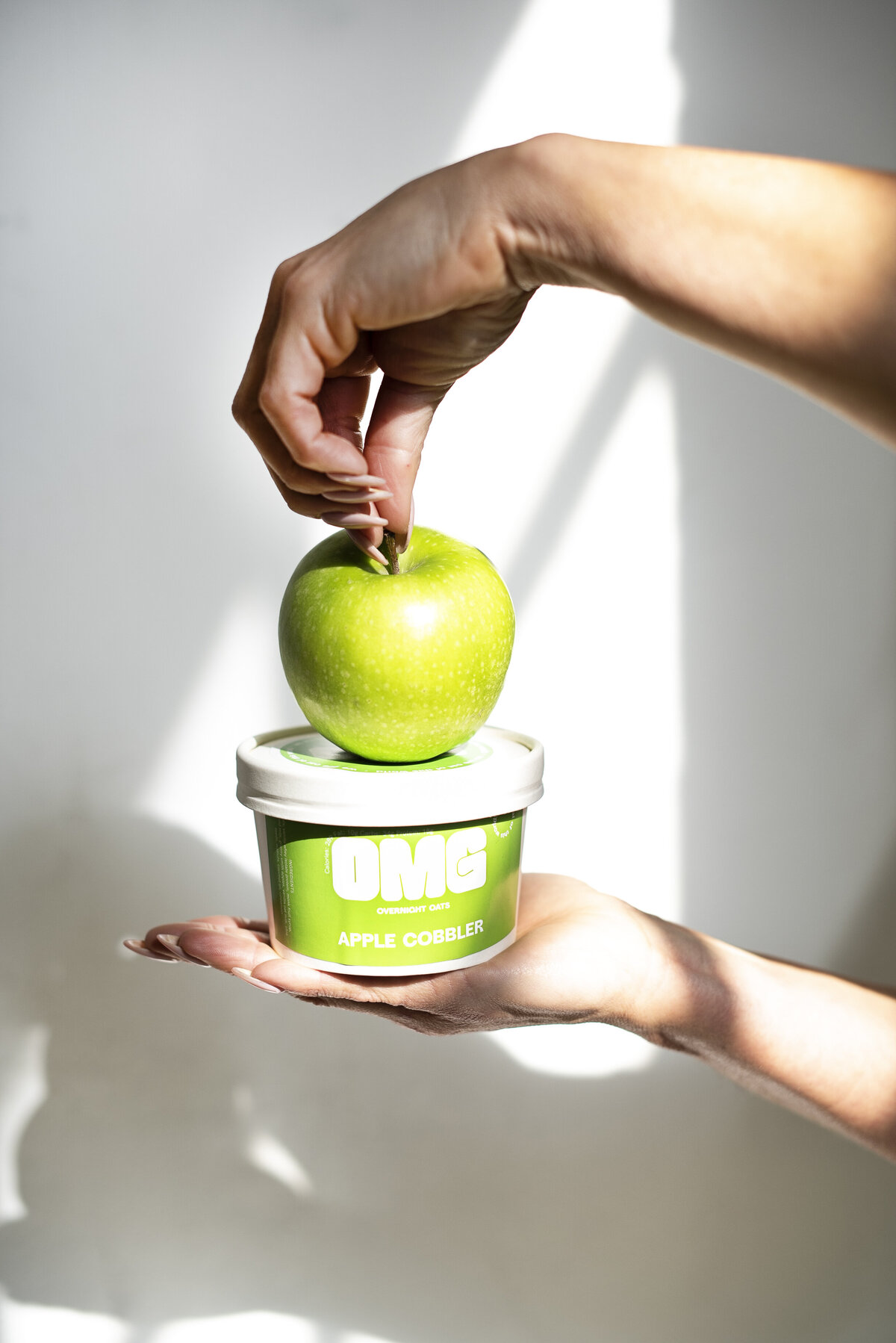 Woman hand holding carton with green apple on top
