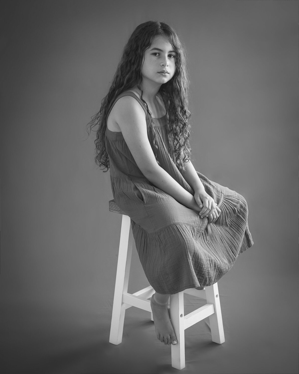 gorgeous black and white portrait of girl on a stool looks almost whimsical or etherial
