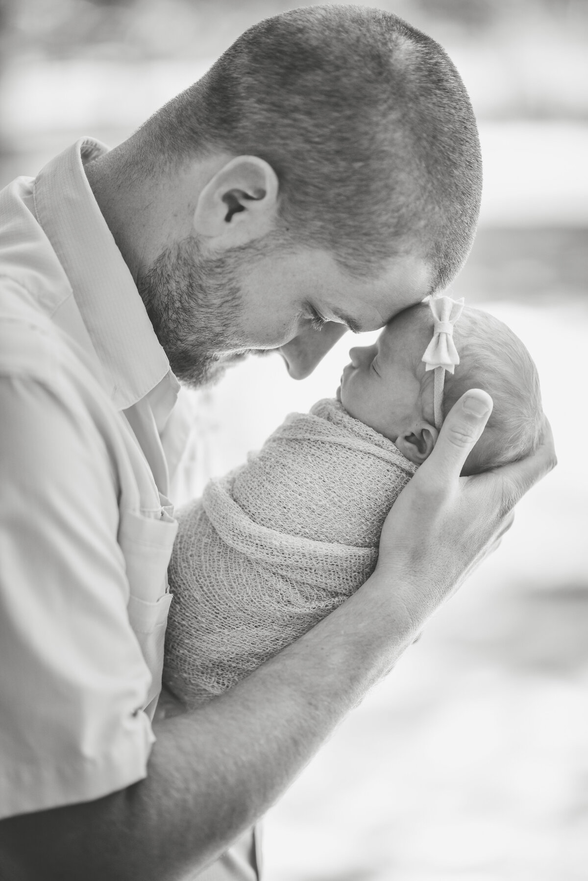 Beautiful lifestyle newborn photography: Black and white of new dad holding newborn girl forehead to forehead in Mississippi