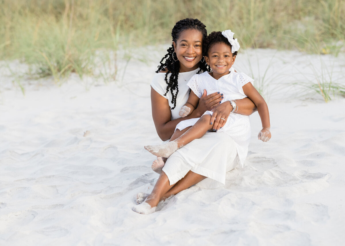 A mom sitting in the sand with her child in her lap near Alys Beach Florida.