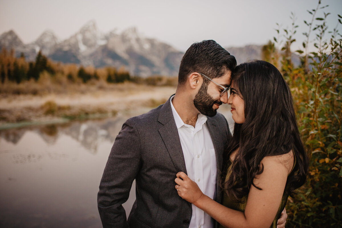man and woman looking at each other as they are forehead to forehead and gently smiling during their fall engagement session in the grand Tetons with photographers in jackson hole
