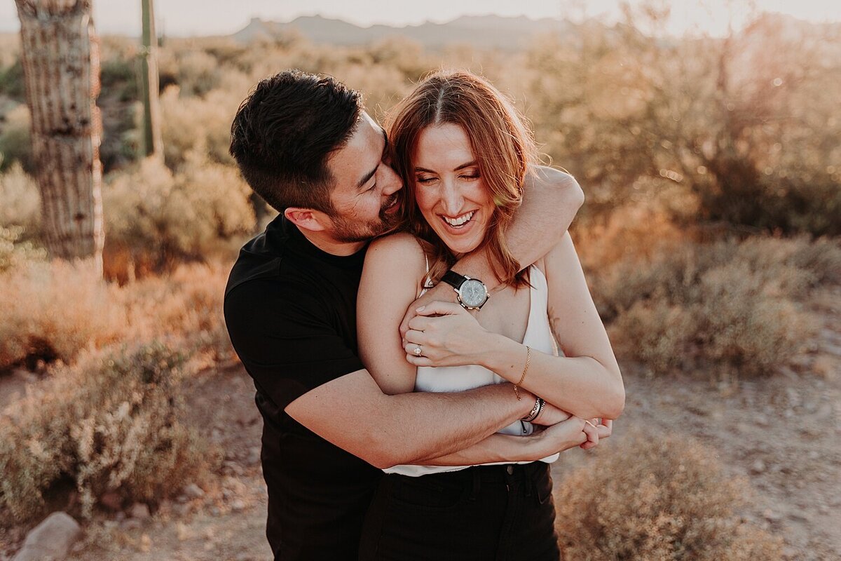 man hugs woman from behind in the desert