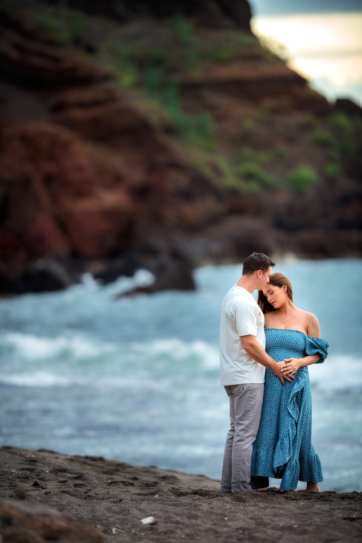 Maui couple snuggling during maternity photoshoot at the beach
