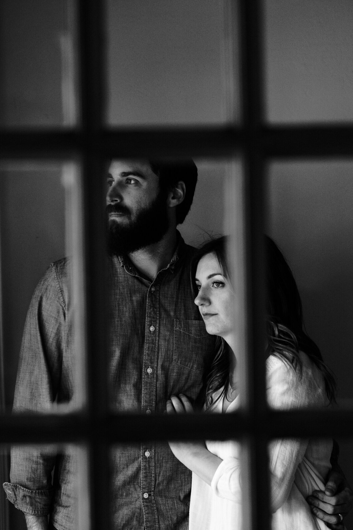 Couple looks out window during their engagement session