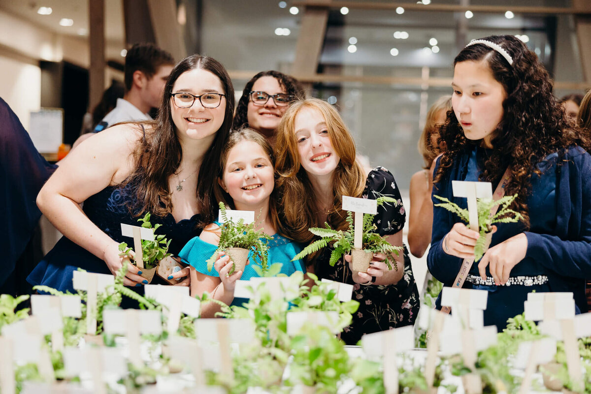 A group of girls collect plants from a party table