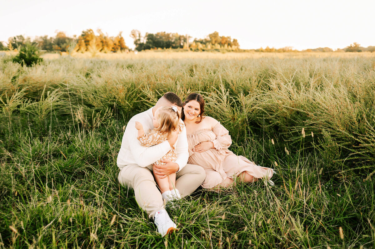 maternity photo of family hugging in field during Springfield MO maternity photography session