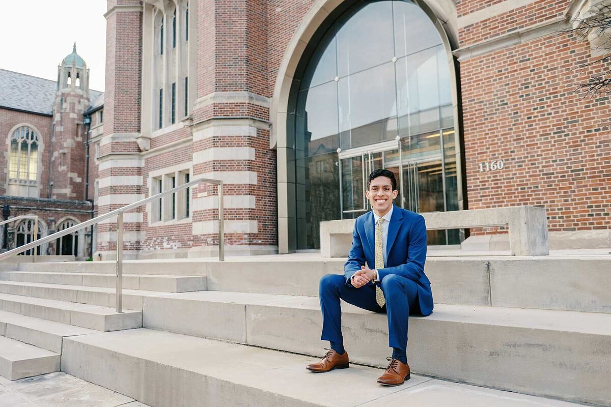 graduating Senior guy wearing a blue suit on his university campus